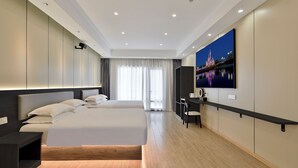 Une chambre d’hôtel moderne avec un grand lit, un bureau et un téléviseur fixé au mur.