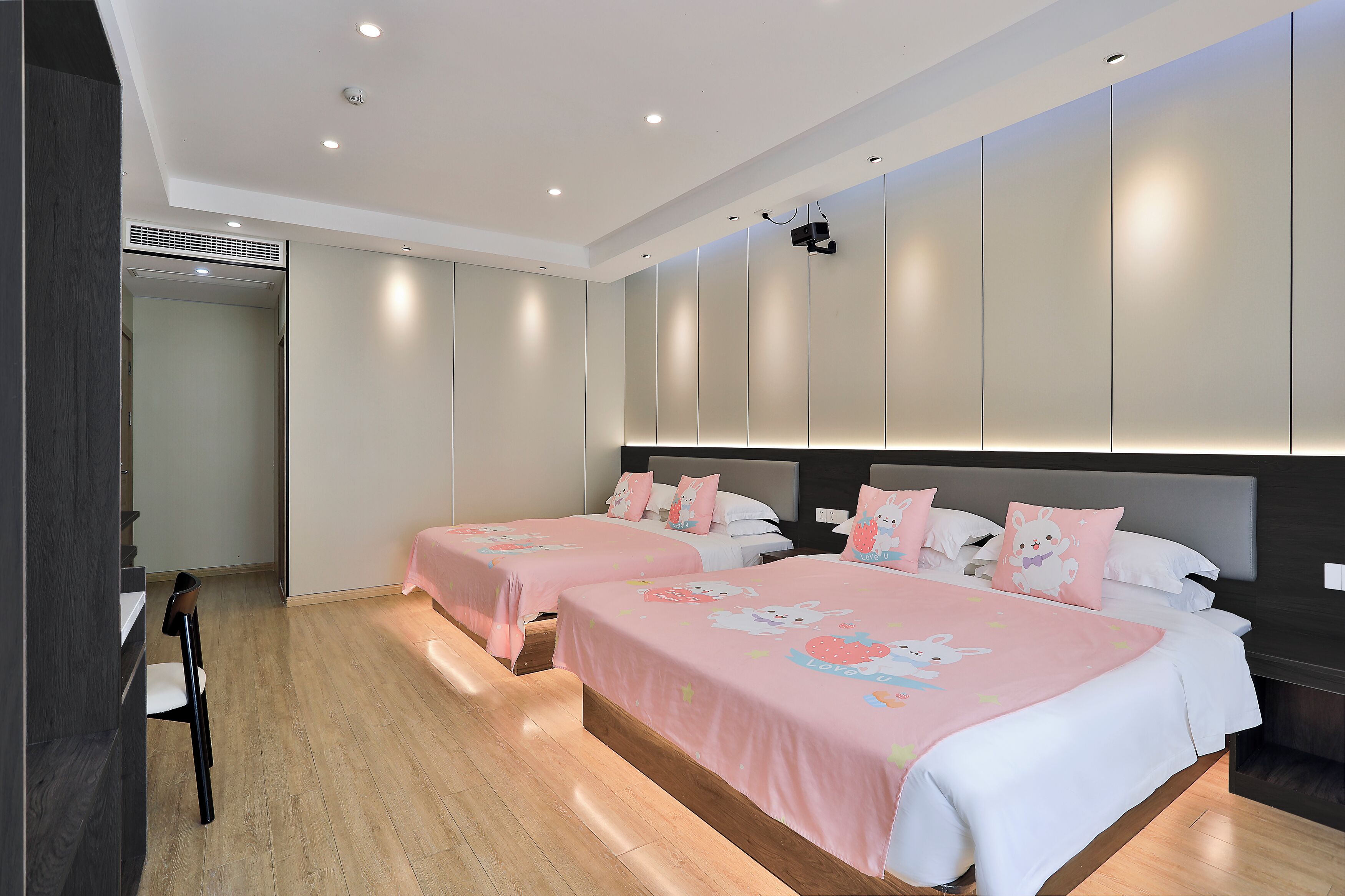 Camera d'albergo con due letti, pavimento in legno e arredamento moderno.