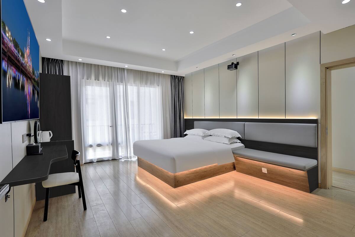 Une chambre moderne avec un grand lit, un bureau et un coin salon.