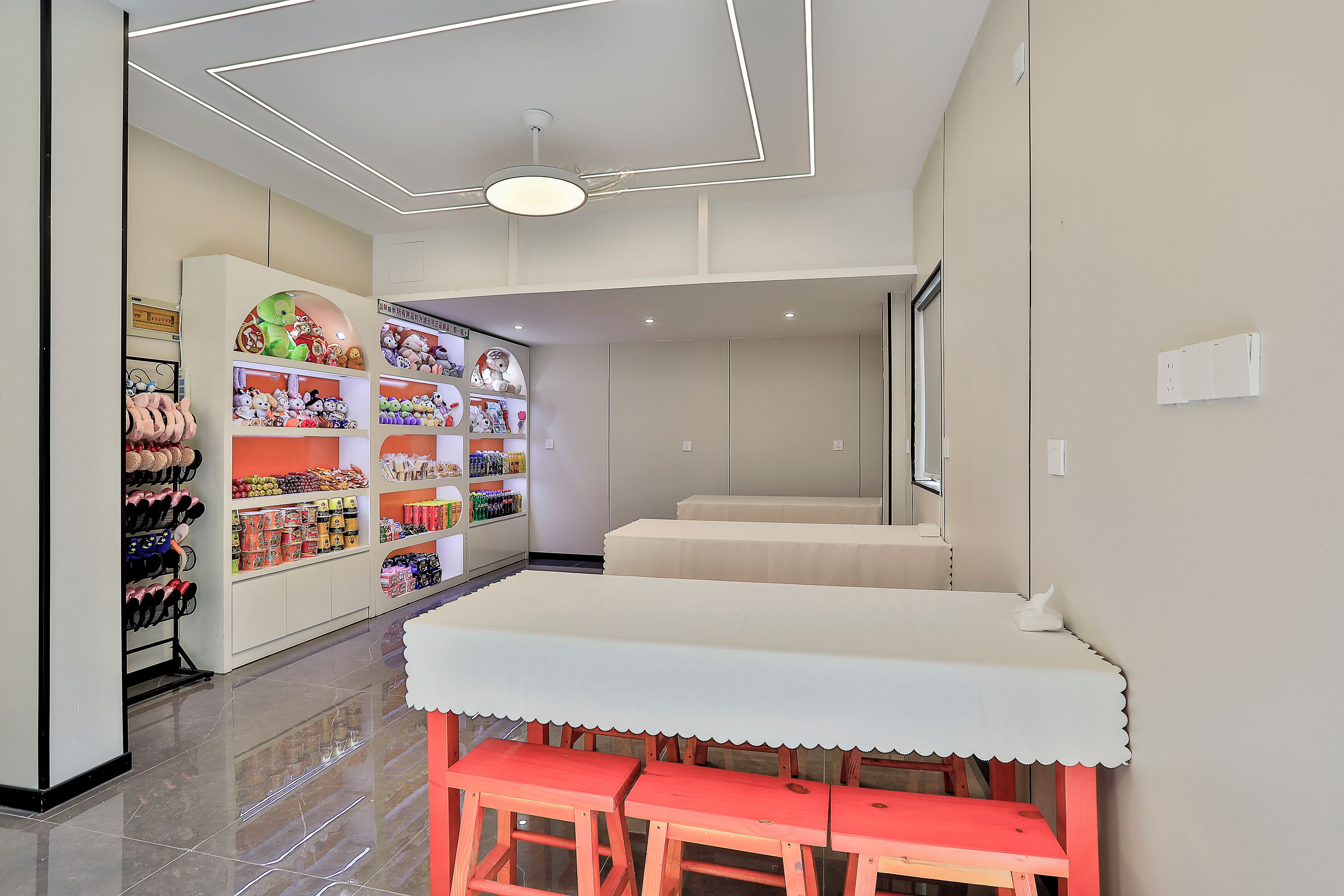 A children's play area with a table and benches, surrounded by shelves stocked with toys and snacks.