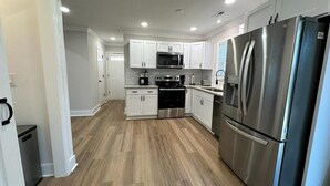 Une cuisine moderne avec des meubles blancs, des appareils en acier inoxydable et un plancher en bois.