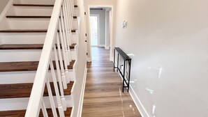 Un escalier avec des rampes blanches et des marches en bois menant à un palier.