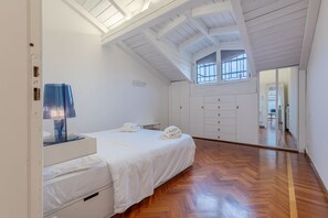 Un dormitorio con cama, mesita de noche, lámpara, armario y ventana con vistas.