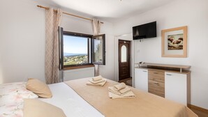 Een slaapkamer met een bed, een bureau, een televisie en een raam met uitzicht.