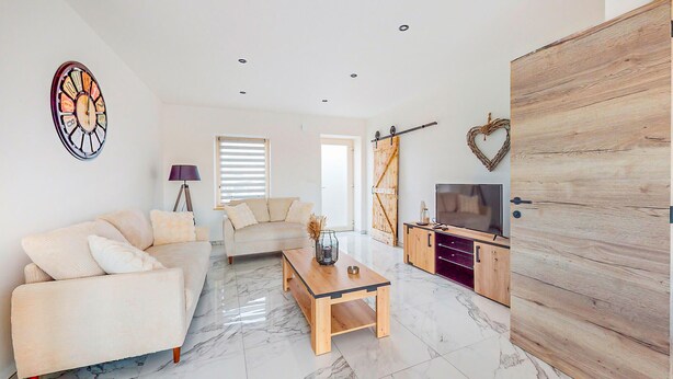Un saló modern amb un sofà, taula de centre, televisió i moble de fusta.