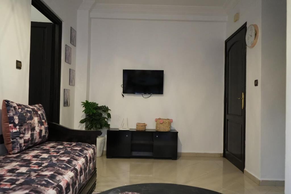 A living room with a sofa, a black entertainment unit, a television, and a door.