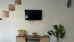 A living room with a flat-screen TV mounted on the wall, a wooden cabinet with decorative baskets, a white router, and a potted plant. - Bayt al atlas (Marrakech)
