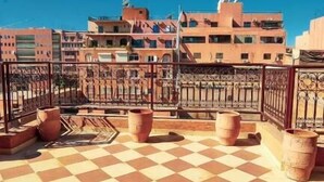 A rooftop terrace with a checkered floor, potted plants, and a view of surrounding buildings. - Bayt al atlas (Marrakech)