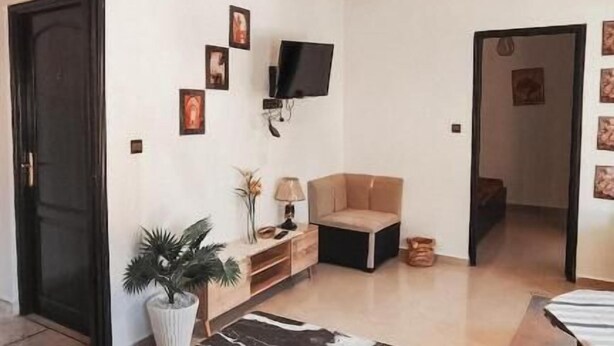 A modern living room with a flat-screen TV, a sofa, a coffee table, and a potted plant. - Bayt al atlas (Marrakech)