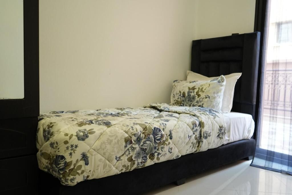 A bedroom with a bed, a headboard, and a window with a view.