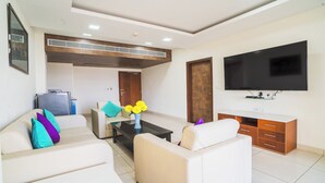 Una sala de estar moderna con un conjunto de sofás, una mesita de centro, un televisor y un mueble de madera.