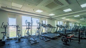 Un gimnasio con equipo de ejercicio diverso, ventanas amplias y piso de baldosas.