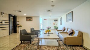 Un vestíbulo amplio con una mesa de recepción, dos sillones, un sofá, una mesita de centro y una alfombra estampada.