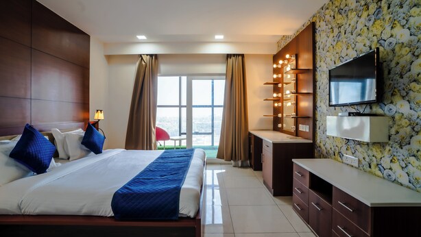 Habitación de hotel con una cama grande, un escritorio, televisión y vistas al exterior.