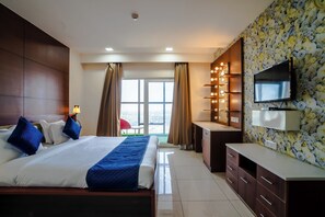 A hotel room with a large bed, a desk, a television, and a view of the outdoors. - Veeva Hotels Jaipur (Jaipur)
