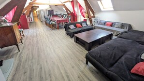 Un loft amplio con techo alto, vigas de madera, una zona de comedor y una acogedora sala de estar.