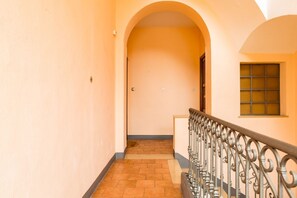 A corridor with a tiled floor, a metal railing, and a door at the end.