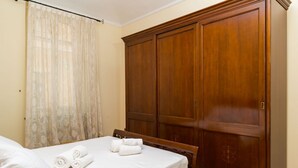 Ein Schlafzimmer mit einem Bett, einem Holzschrank und einem Fenster mit durchsichtigen Vorhängen.