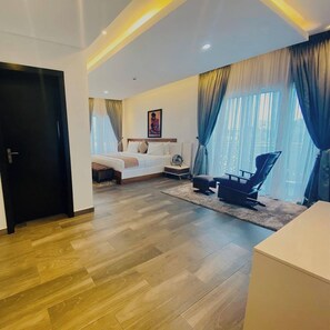 A modern hotel room with a large bed, a desk, and a chair. - Crystal House Shortlets (Lagos)
