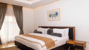 A modern bedroom with a large bed, a bedside table, a ceiling light, and a painting on the wall.