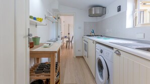 Uma cozinha compacta com máquina de lavar, uma mesa de jantar e uma janela.