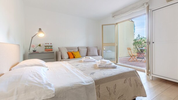 Quarto com cama, mesa de cabeceira, abajur e vista para o exterior.