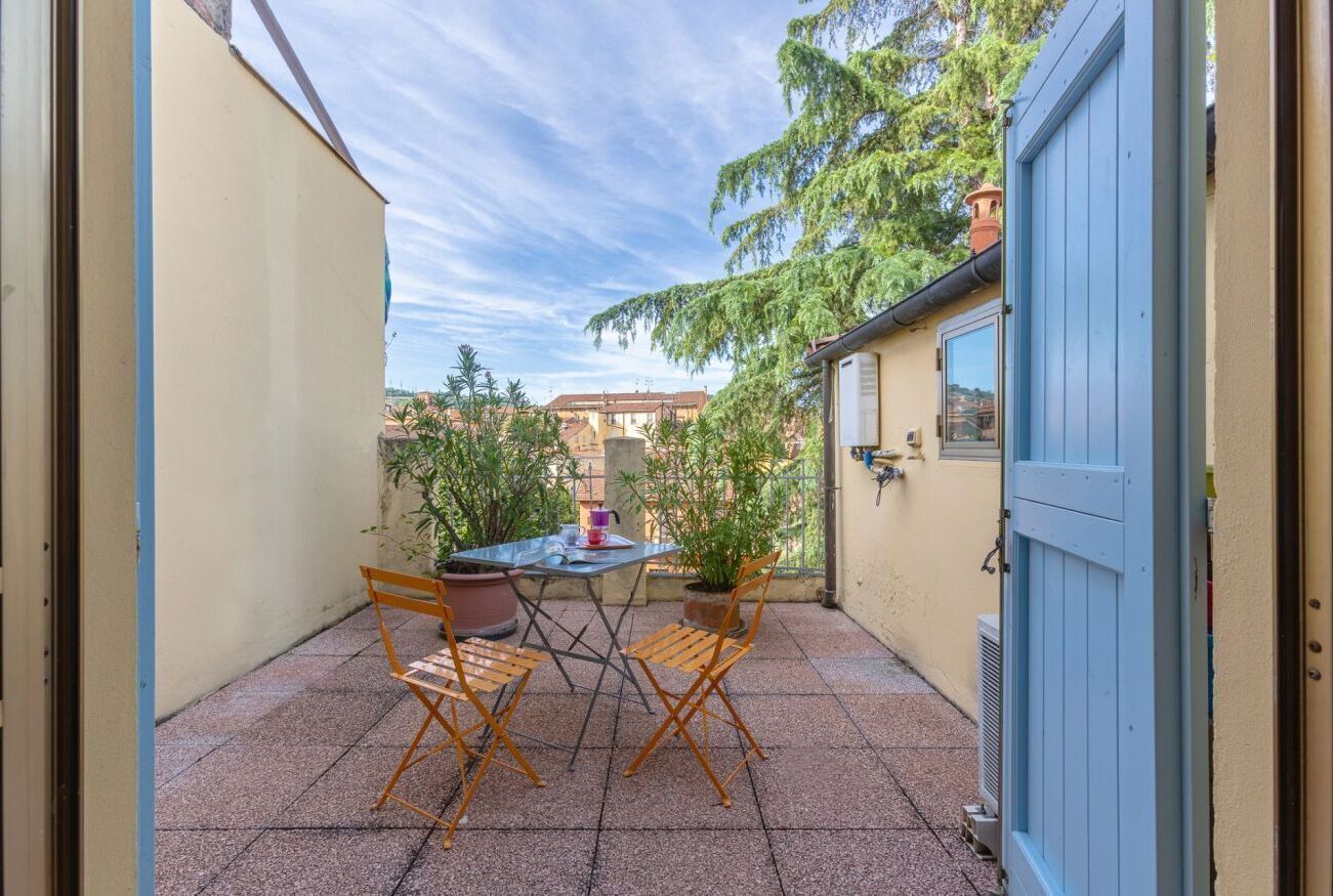 Une terrasse avec une table et des chaises, des plantes en pot et une porte bleue.
