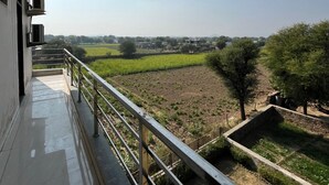 Ein Balkon mit Blick auf ein grünes Feld und Bäume.