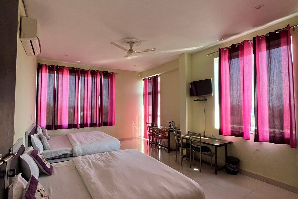 A hotel room with a large bed, a desk, and a chair.