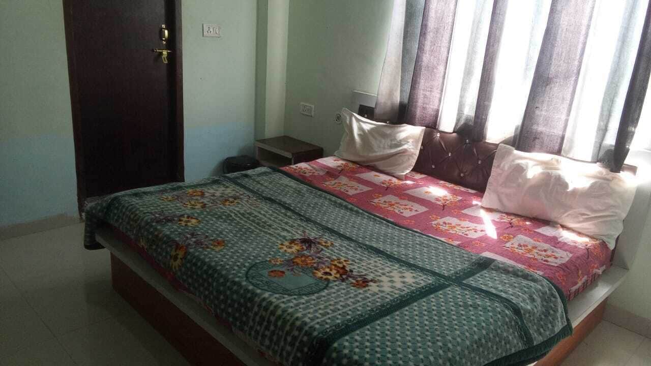 A bedroom with a bed, a nightstand, a door, and a window with curtains.