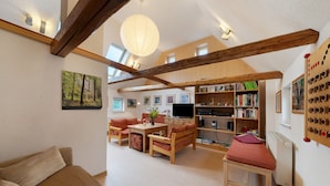 Un salon confortable avec un canapé, des meubles en bois, un téléviseur, des étagères et une grande fenêtre.