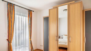 A bedroom with a bed, a wardrobe, and a curtain. - Apartment 'Tannenblick 1-1' with Mountain View, Private Terrace and Wi-Fi (Oberhof)