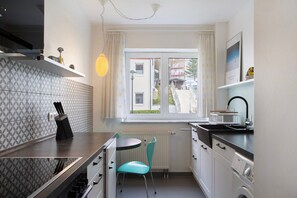 A compact kitchen with a window, a radiator, a sink, and a chair. - Apartment 'Tannenblick 6-2' with Mountain View, Balcony and Wi-Fi (Oberhof)