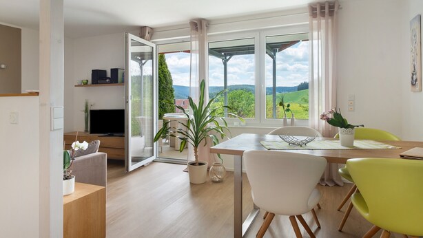 Ein moderner Essbereich mit Tisch, Stühlen und Blick ins Freie.
