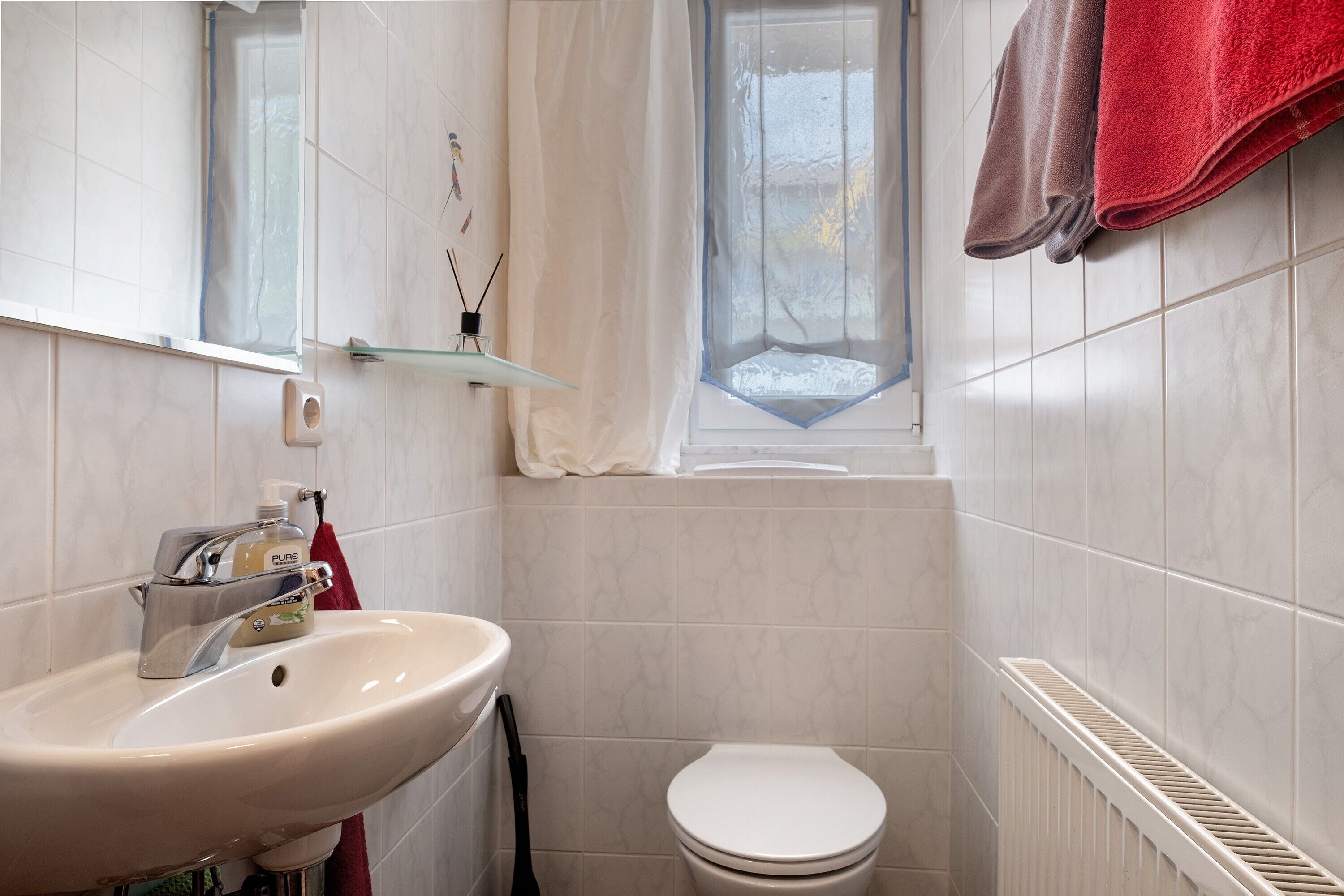 Ein Badezimmer mit Waschbecken, Toilette, Fenster und Handtuchhalter.