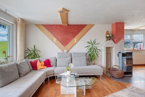 Un salon moderne avec un canapé d’angle, une table basse en verre et une cheminée.