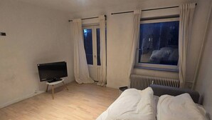 A bedroom with a bed, a TV, a window with curtains, and a radiator. - Gentofte Cozy Private Apartment (Gentofte)