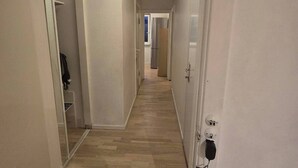 A hallway with a wooden floor, white walls, and a door on the right. - Gentofte Cozy Private Apartment (Gentofte)