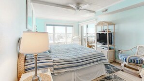 Ein Schlafzimmer mit Bett, Fernseher, Sessel und Balkon.