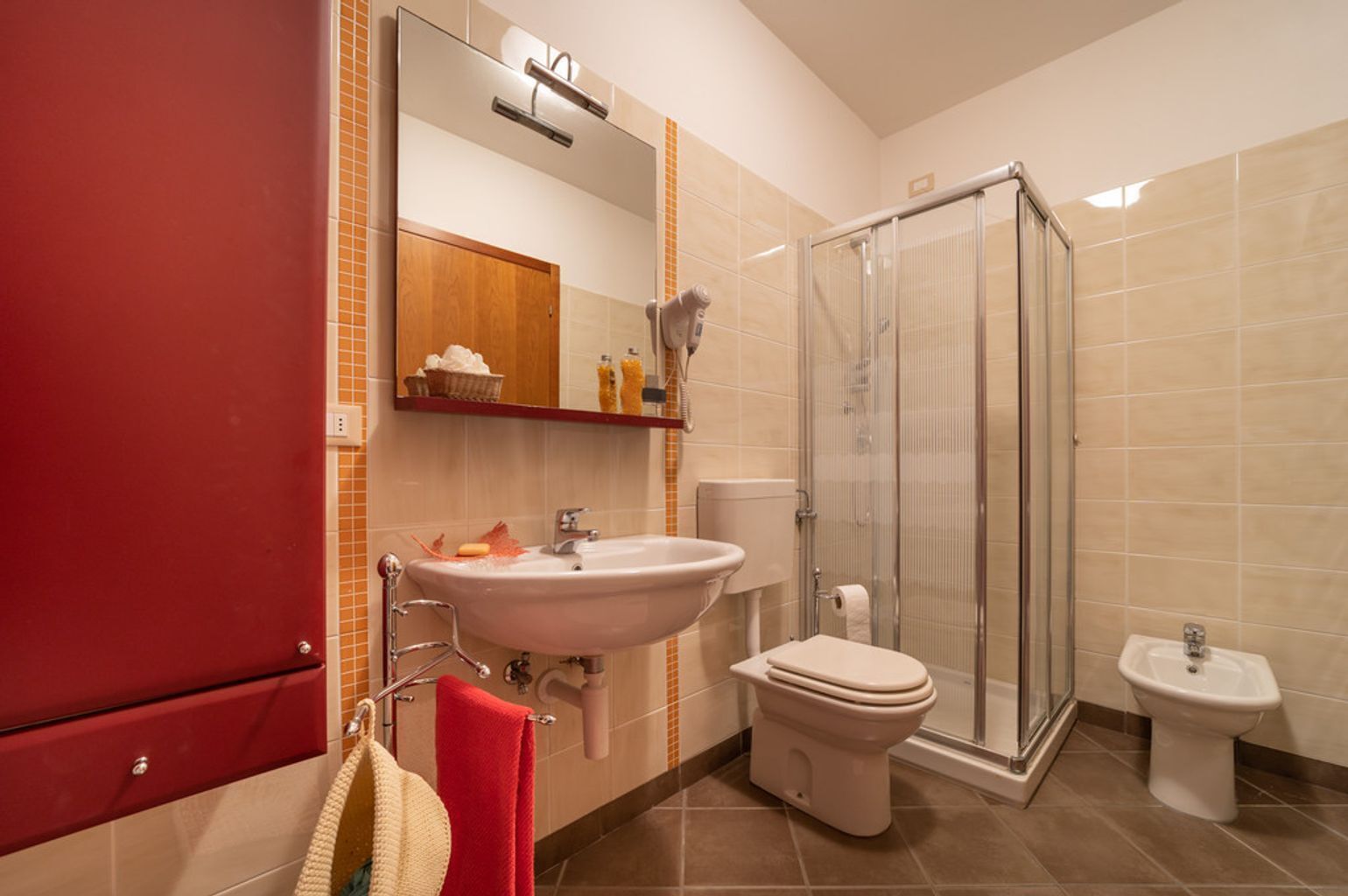 A bathroom with a sink, toilet, bidet, and a glass shower enclosure.