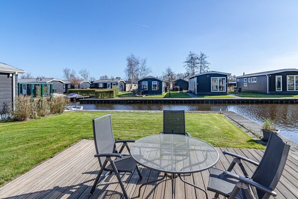 Outdoor dining - Comfortable 4-person chalet by the canal with a fully equipped kitchen, two bedrooms, terrace, storage room with washing machine, and free WiFi. (Giethoorn)