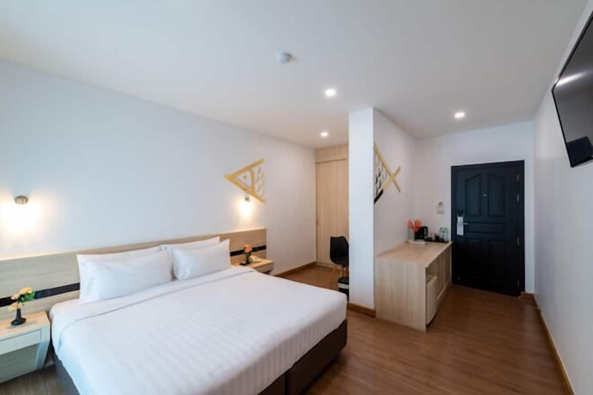 Ein Hotelzimmer mit Bett, Nachttisch, Lampe und Schreibtisch mit Stuhl.