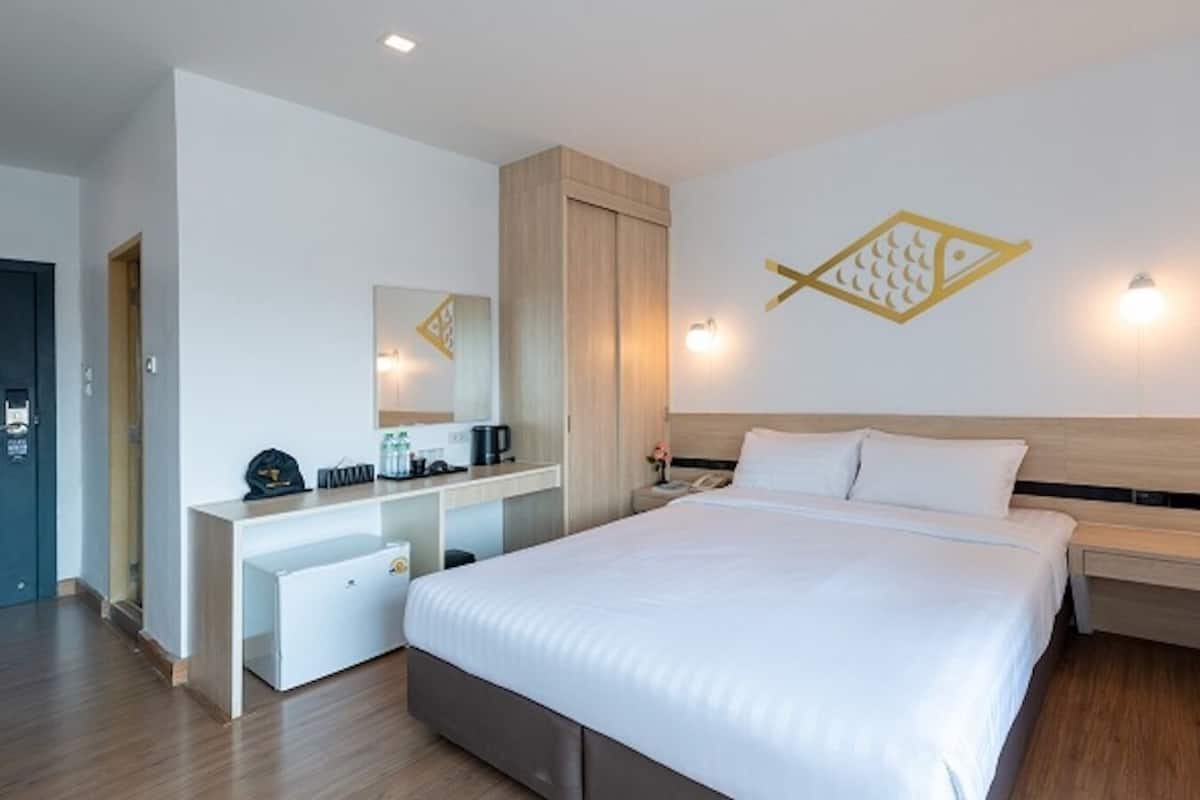 Ein modernes Hotelzimmer mit einem großen Bett, einem Schreibtisch mit Computer, einem Spiegel und einer Wanddekoration in Form eines Fisches.