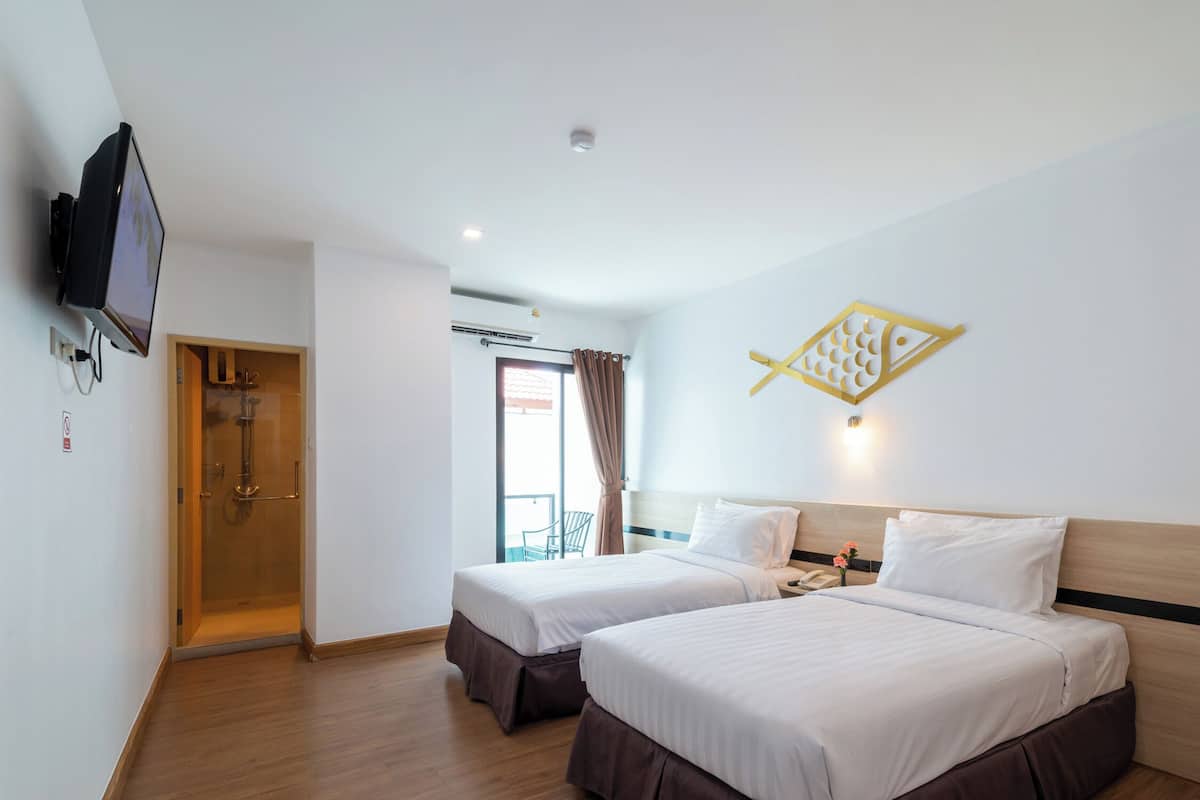 Ein Hotelzimmer mit zwei Betten, einer Dusche, einem Fernseher und einem Balkon mit einem Stuhl.
