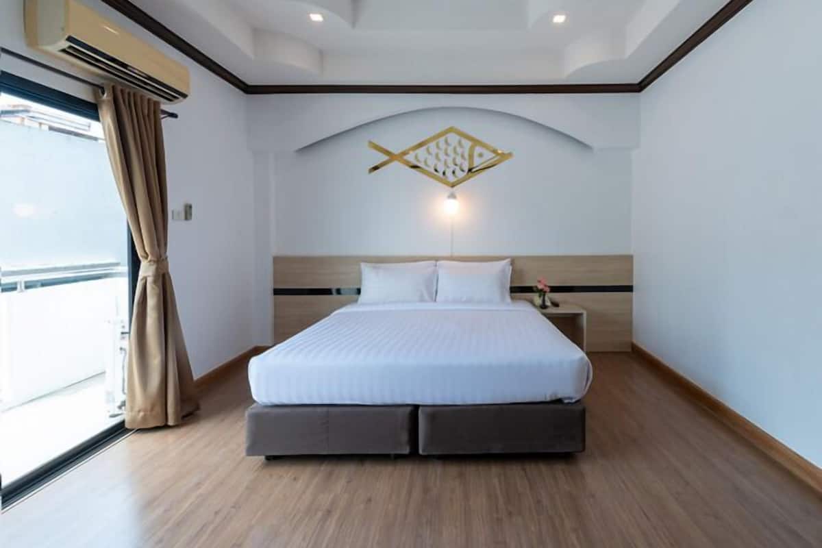 Ein Hotelzimmer mit einem großen Bett, einer Deckenleuchte und einem Fenster mit Vorhängen.