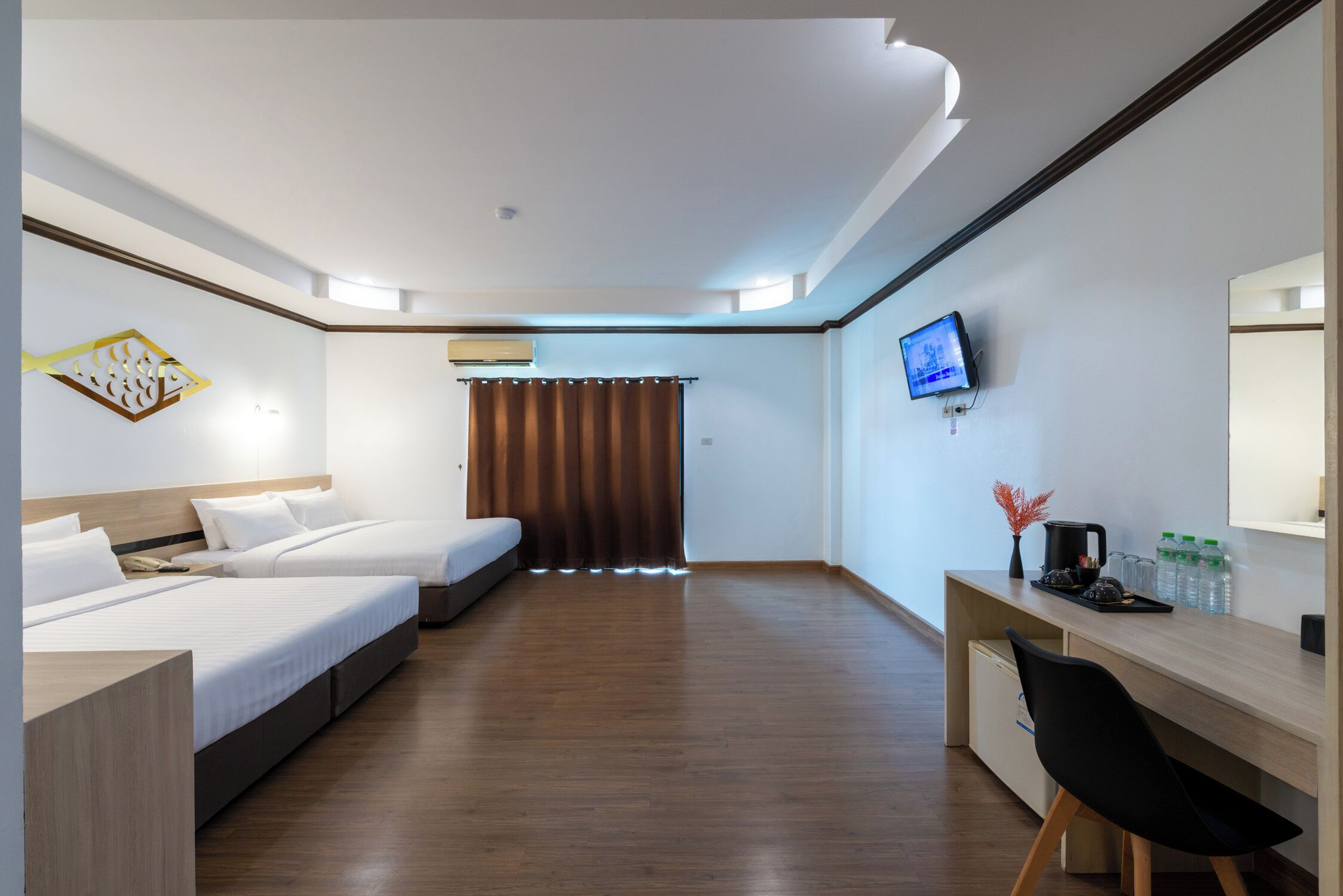 A hotel room with two beds, a desk with a chair, a television, and a window with curtains.