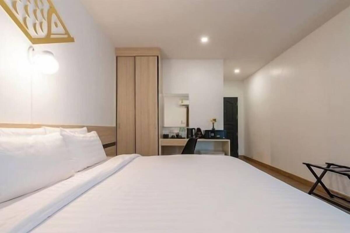 Quarto de hotel com cama, escrivaninha, cadeira e guarda-roupa.