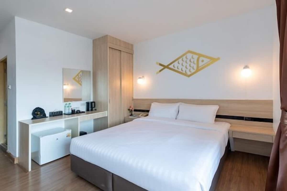 Ein Hotelzimmer mit Bett, Schreibtisch, Spiegel und Wand mit einer leuchteform in Fischform.