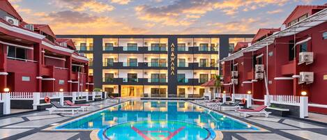 A hotel with a swimming pool, multiple balconies, and a red and black color scheme.
