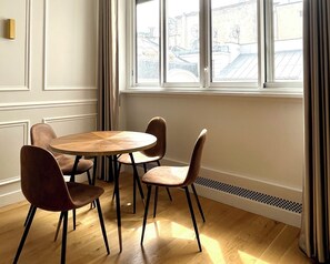 Enjoy a city view from the comfort of this room, featuring a round table and four chairs, a large window, and paneling on the walls.